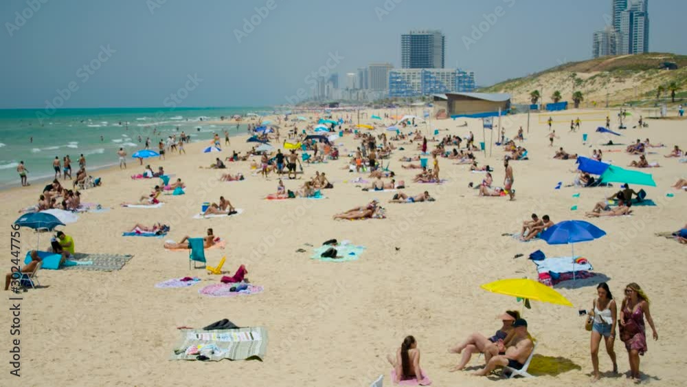 Time lapse view of the Beach showing relaxing tanning people on sand with towels and colourful umbrellas. Timelapse footage of enjoying crowed at the beach on a summer day. Time lapse view of the Beach showing relaxing tanning people on sand with towels and colourful umbrellas. Timelapse footage of enjoying crowed at the beach on a summer day.