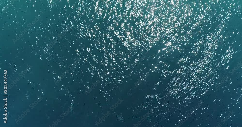 Stunning top down Aerial Drone Footage Of Clear Sea Ocean Water With Small ripples, sun reflection and caustic waves. Blue and green soft wave sea in deep calm flat water.