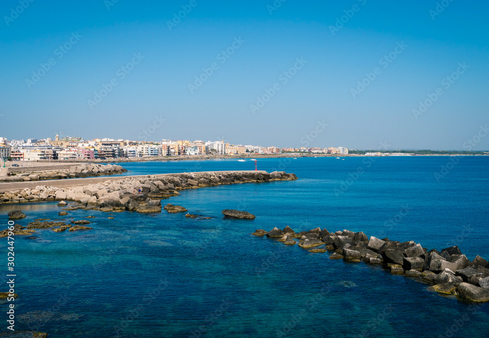Pier with big stones in the mediterranean harbor at the travel destination Gallipoli in Puglia on a deep blue ocean