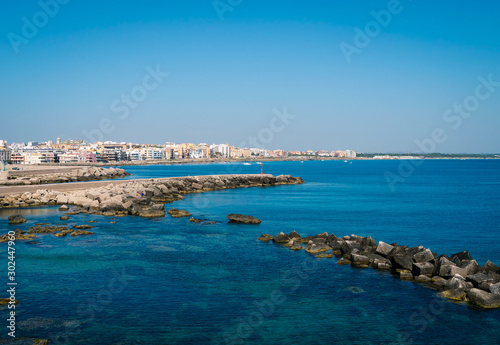 Pier with big stones in the mediterranean harbor at the travel destination Gallipoli in Puglia on a deep blue ocean