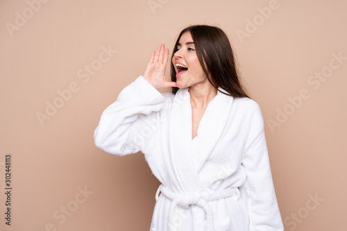 Young girl in a bathrobe over isolated background shouting with mouth wide open