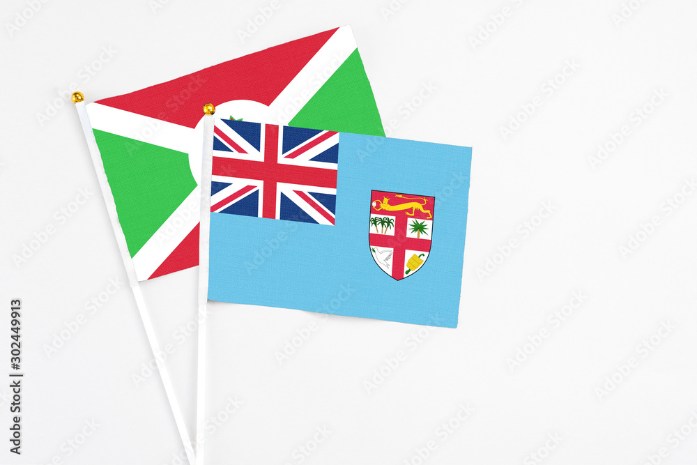Fototapeta premium Fiji and Burundi stick flags on white background. High quality fabric, miniature national flag. Peaceful global concept.White floor for copy space.