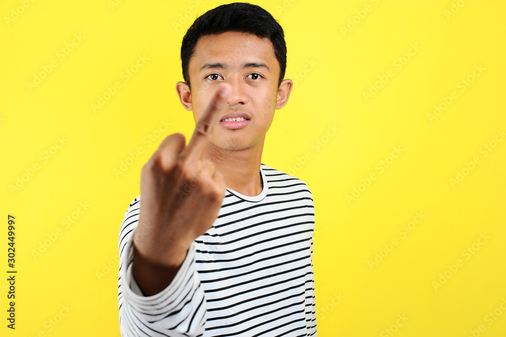 Young Asian man showing middle finger doing fuck you bad expression, provocation and rude attitude Young Asian man showing middle finger doing fuck you bad expression, provocation and rude attitude