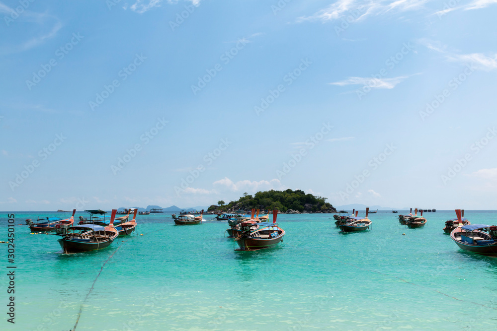 Koh Lipe, Andaman sea, Thailand. Beautiful Island of Koh Lipe, Long-tailed boat parking during Sunrise and Sunset by the beach. Beautiful white beach, blue sea with long tail boats in summer.