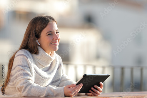 Woman listening to music with a tablet looks away