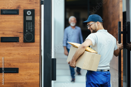 Happy postal worker delivering packages to customer's home.