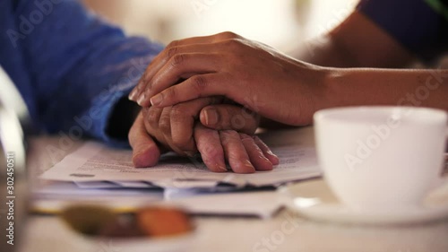 Close-up of hands giving care by a caretaker to a senior woman. Different races. Black hands, white hands..