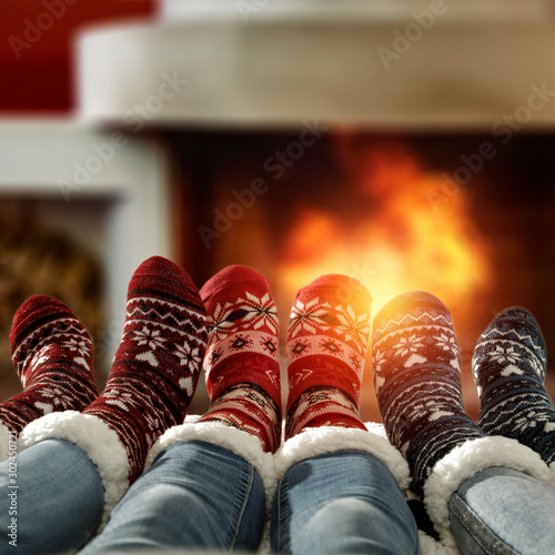 Woman legs with christmas woolen socks and home interior with fireplace.Free space for your decoration and xmas december cold night.