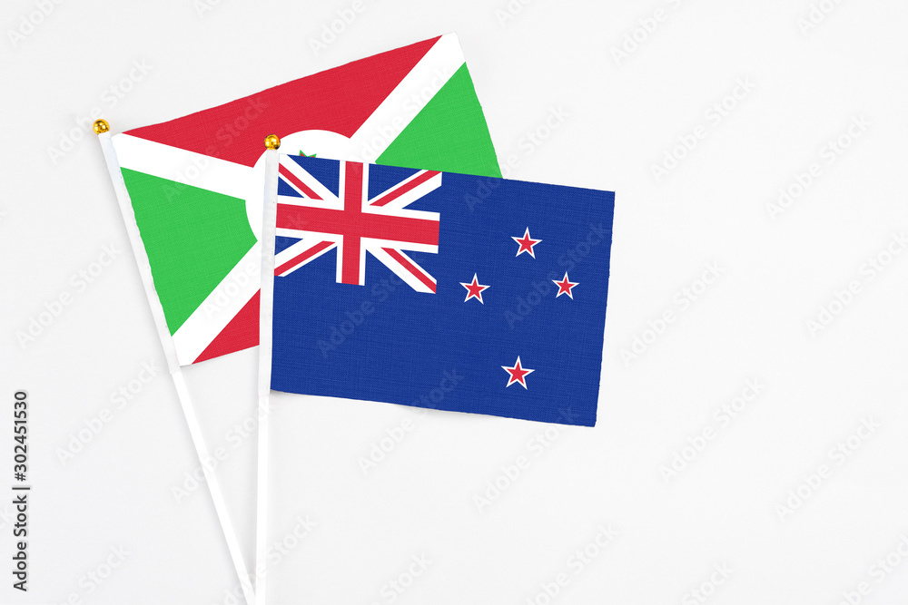 Fototapeta premium New Zealand and Burundi stick flags on white background. High quality fabric, miniature national flag. Peaceful global concept.White floor for copy space.