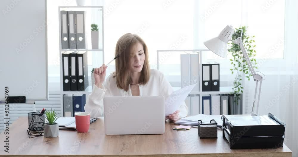 Happy businesswoman discussing paperwork by video conference using office laptop Happy businesswoman discussing paperwork by video conference using office laptop