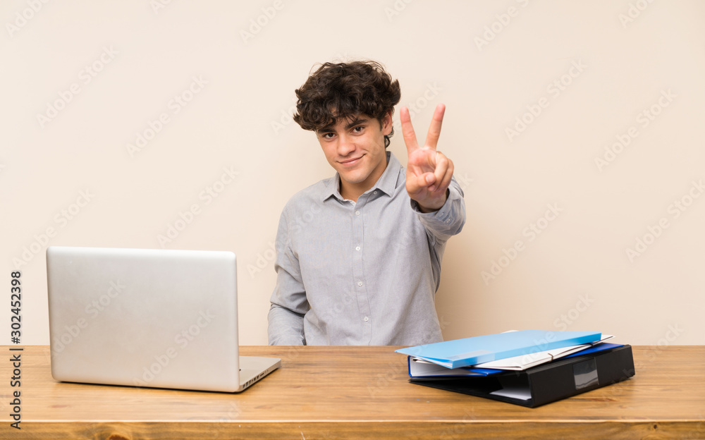 Young student man with a laptop smiling and showing victory sign Young student man with a laptop smiling and showing victory sign