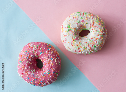 Delicious doughnuts with sprinkles on color background