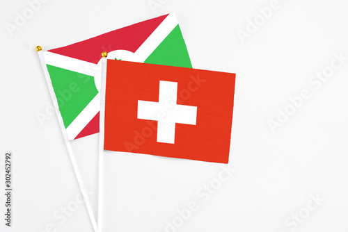 Switzerland and Burundi stick flags on white background. High quality fabric, miniature national flag. Peaceful global concept.White floor for copy space. photo