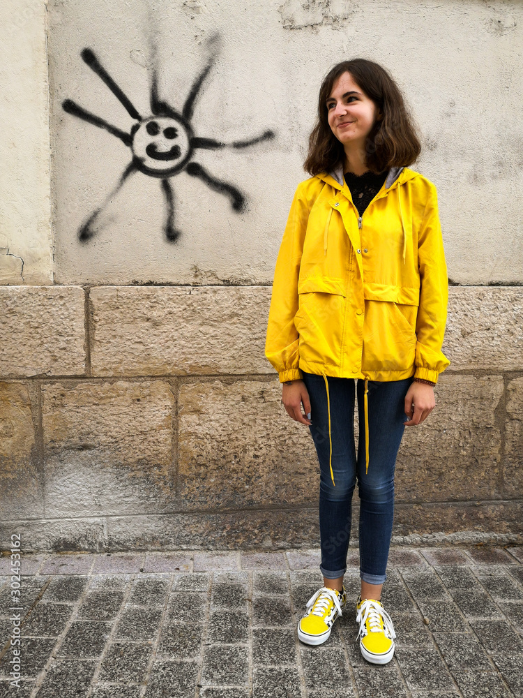 une jeune femme avec un ciré jaune vers un dessin de soleil pour la météo  Stock Photo | Adobe Stock