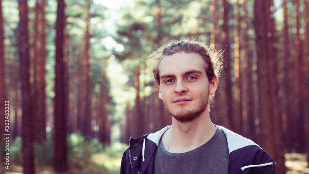 Young man with slight beard in forest Young man with slight beard in forest