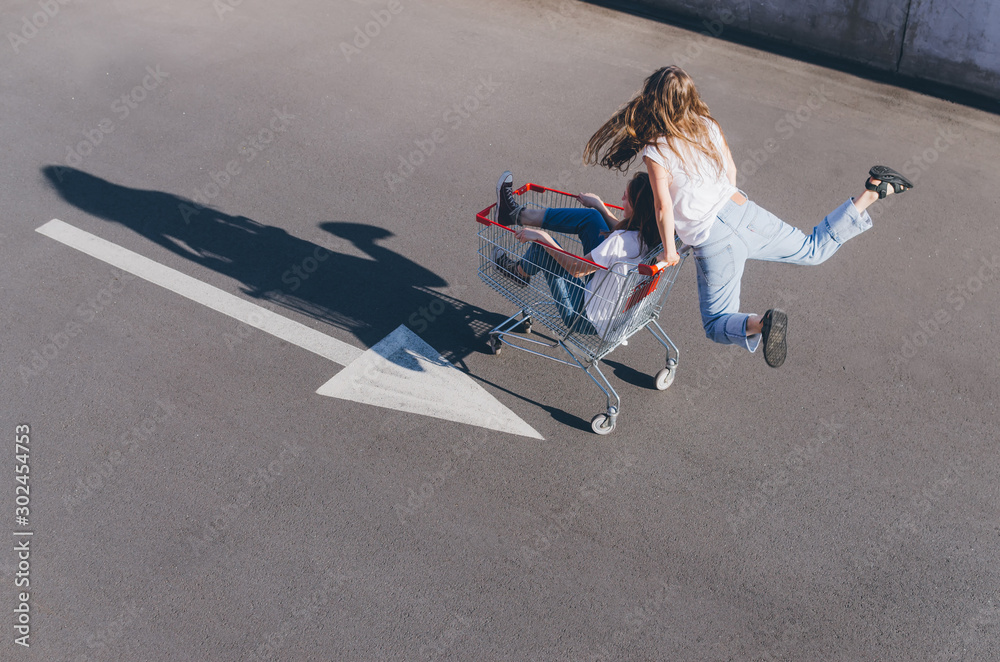 Two happy hipster girls having fun with shopping cart outdoors Two happy hipster girls having fun with shopping cart outdoors