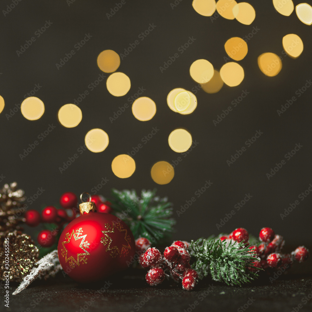 New Year and Christmas decoration, holiday background. Red festive ball bauble, green fir (xmas tree) and yellow blurred lights. Toned on vintage style.