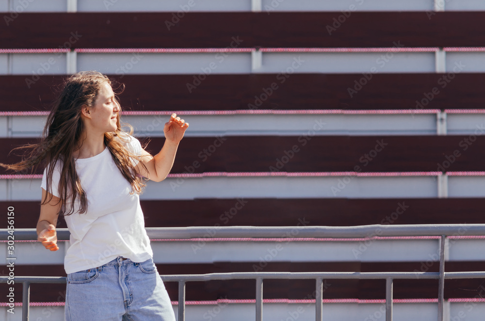 Obraz premium Young hipster woman leaning back on fence and making fun in front of urban wall