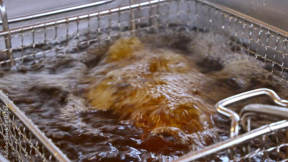 Fryer from the food net is lowered into boiling oil in an outdoor fast-food restaurant Fryer from the food net is lowered into boiling oil in an outdoor fast-food restaurant