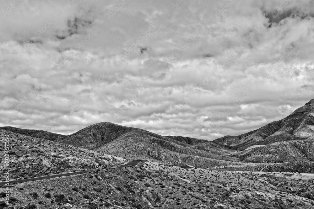 empty mysterious mountainous landscape from the center of the Canary Island Spanish Fuerteventura with a cloudy sky empty mysterious mountainous landscape from the center of the Canary Island Spanish Fuerteventura with a cloudy sky
