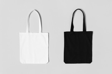 White and black tote bags mockup on a grey background.