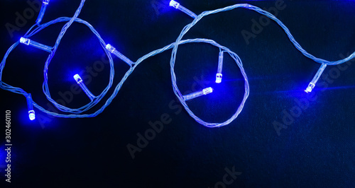 Dark textured christmas background with blue christmas garland. Background for banner, copyspace.view from above.