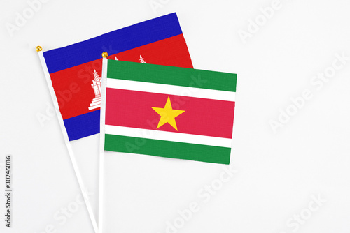 Suriname and Cambodia stick flags on white background. High quality fabric, miniature national flag. Peaceful global concept.White floor for copy space.