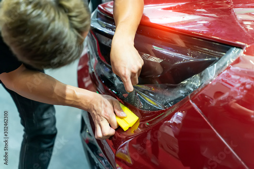 Foto Worker install car paint protection film with spatula