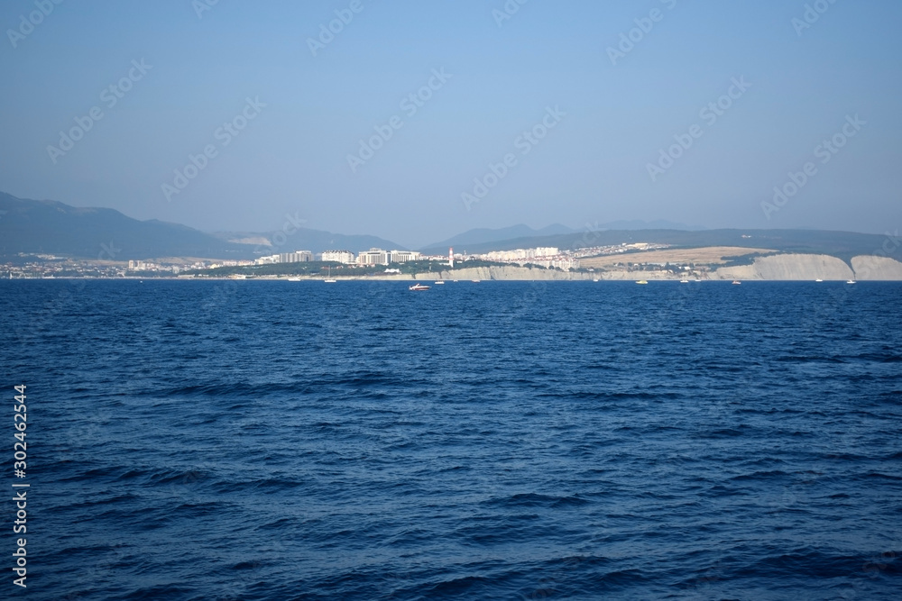 The view from the sea to the coast and mountains in the background on a sunny day