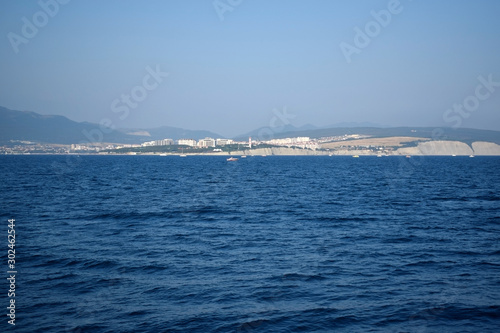 The view from the sea to the coast and mountains in the background on a sunny day