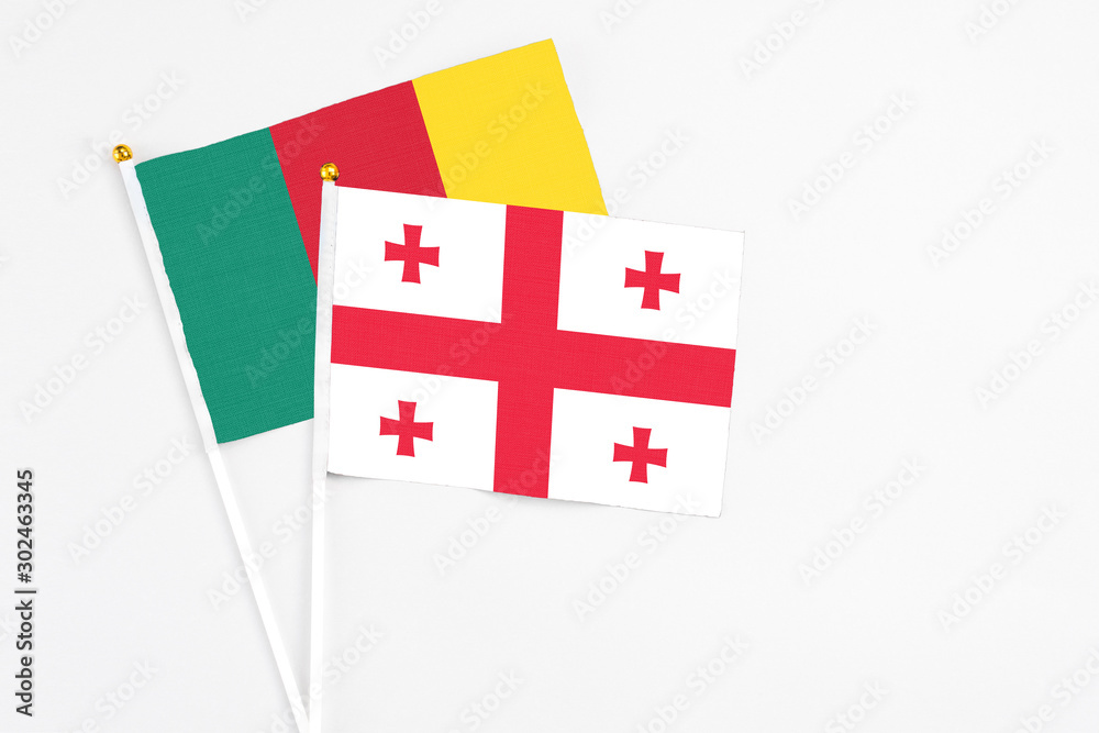 Georgia and Cameroon stick flags on white background. High quality fabric, miniature national flag. Peaceful global concept.White floor for copy space.