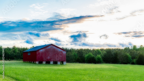Red barn in a field with sky and clouds in the background