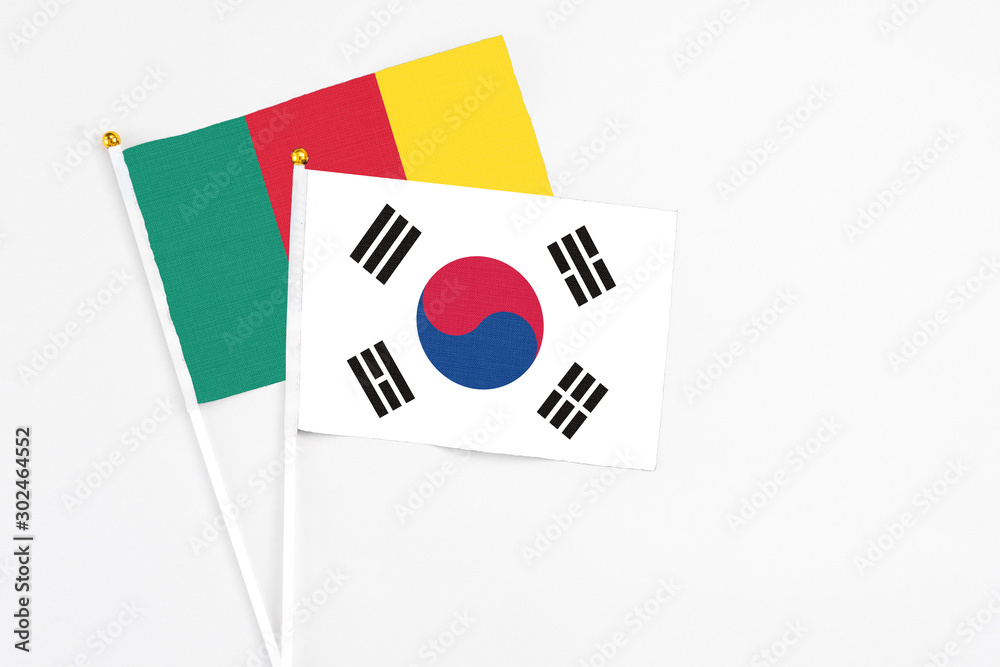 South Korea and Cameroon stick flags on white background. High quality fabric, miniature national flag. Peaceful global concept.White floor for copy space.
