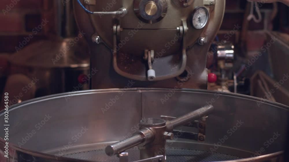 Barista checks the coffee beans being roasted if it is ready to be sifted at a cafe house Barista checks the coffee beans being roasted if it is ready to be sifted at a cafe house