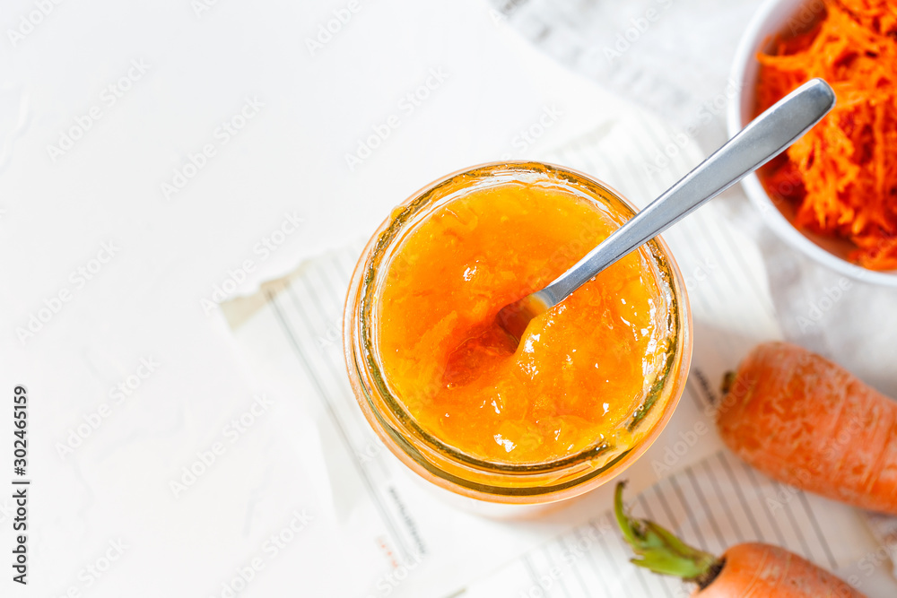 Vegetarian carrot jam or marmalade with orange juice in a glass jar on a white background top view close-up copy space for text.Healthy organic vegetable dessert for breakfast.Horizontal orientation Vegetarian carrot jam or marmalade with orange juice in a glass jar on a white background top view close-up copy space for text.Healthy organic vegetable dessert for breakfast.Horizontal orientation