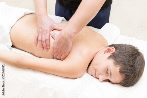 Medical sports massage of the feet of a boy in a massage room on a white background.