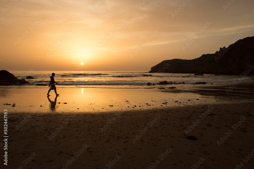 Hombre andando por la playa al atardecer