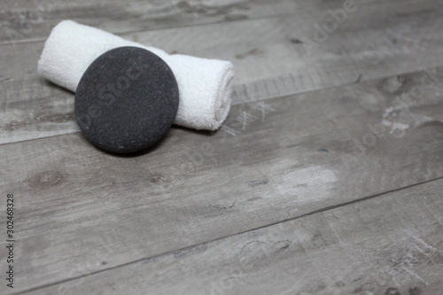 Hot stone leaning on rolled white towel on wooden background