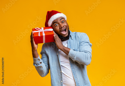 Crazy black guy in Santa hat holding Christmas gift box photo