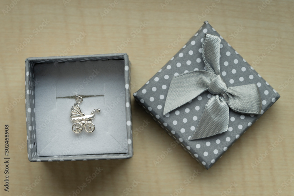 Silver pendant in a box in the shape of a stroller. Silver pendant in a box in the shape of a stroller.