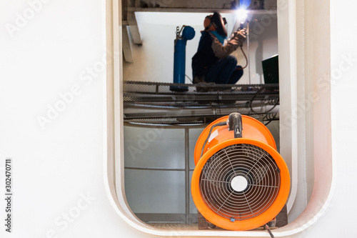 Mobile ventilation fan installed to ventilate air pollution in welding of structural steel working in confined spaces area at site construction. Ventilation system safety concept.