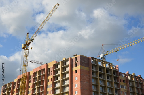 Working on place with many tall buildings under construction and cranes under a blue sky