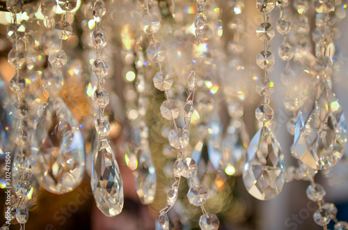 Crystals of a crystal chandelier with glow and refraction of light. Multi-colored glare on transparent crystals. A curtain of crystal droplets.