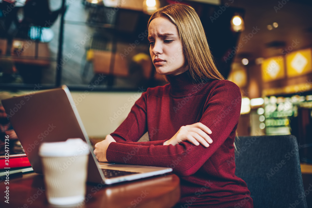 Fototapeta premium Piękna smutna, utalentowana studentka czuje się zmęczona podczas oglądania nudnego webinarium szkoleniowego na stronie internetowej na laptopie podłączonym do internetu.