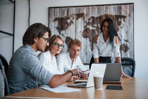 Sits by the table with laptops. Young business people in formal clothes working in the office photo