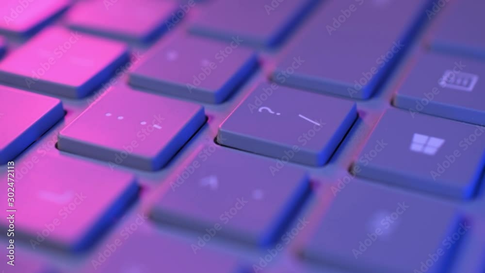 Keyboard keys close up tracking shot in blue and pink colorful light Keyboard keys close up tracking shot in blue and pink colorful light