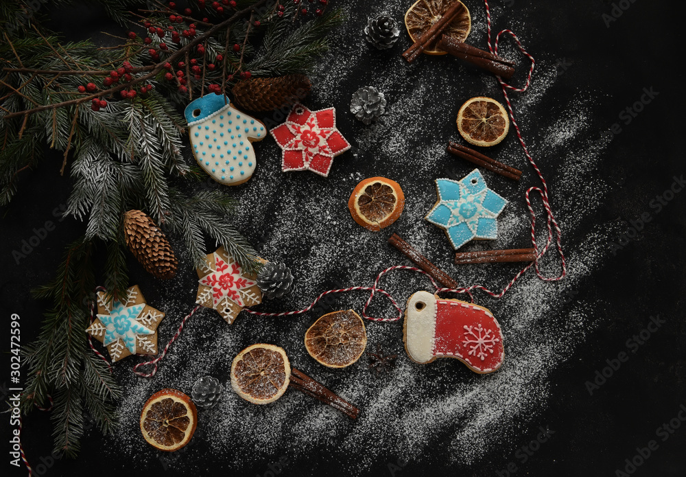 Gingerbread cookies and Christmas cookies among the branches of a Christmas tree in artificial snow on a black background. Christmas decorations, postcard. Preparing for the New Year and Christmas hol