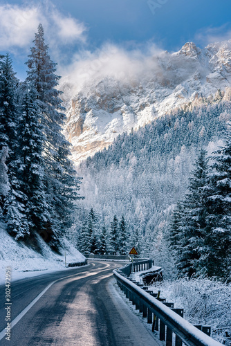 Curved road in the Italian Alps in South Tyrol, during winter / Sunny winter day with harsh shadows and lot of snow