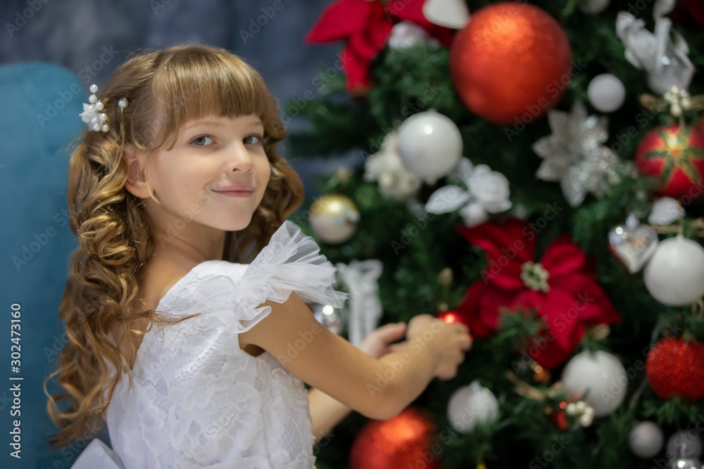 A beautiful child decorates a Christmas tree. Elegant girl in christmas time. A beautiful child decorates a Christmas tree. Elegant girl in christmas time.