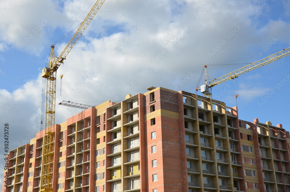 Working on place with many tall buildings under construction and cranes under a blue sky Working on place with many tall buildings under construction and cranes under a blue sky